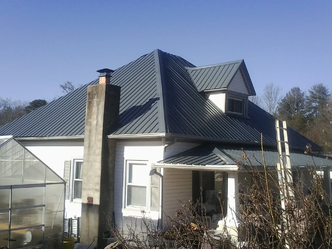Dark blue standing seam metal roof on a white farmhouse with dormer — Slate & Tile Roof Repair by Roofing Brothers in Fishing Creek