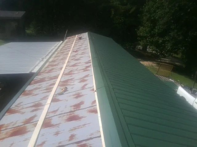 Old rusted panels beside newly installed green metal roofing — Wind Damage Roof Repair by Roofing Brothers in Fishing Creek