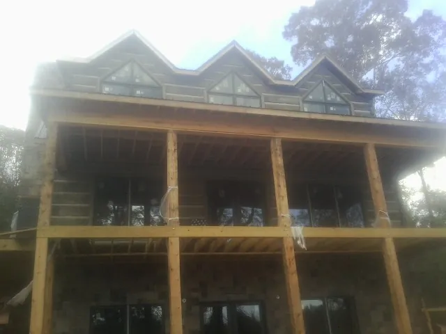 Dormers and porch framing on a large log home under construction — Roof Coating work by our crew in Fishing Creek