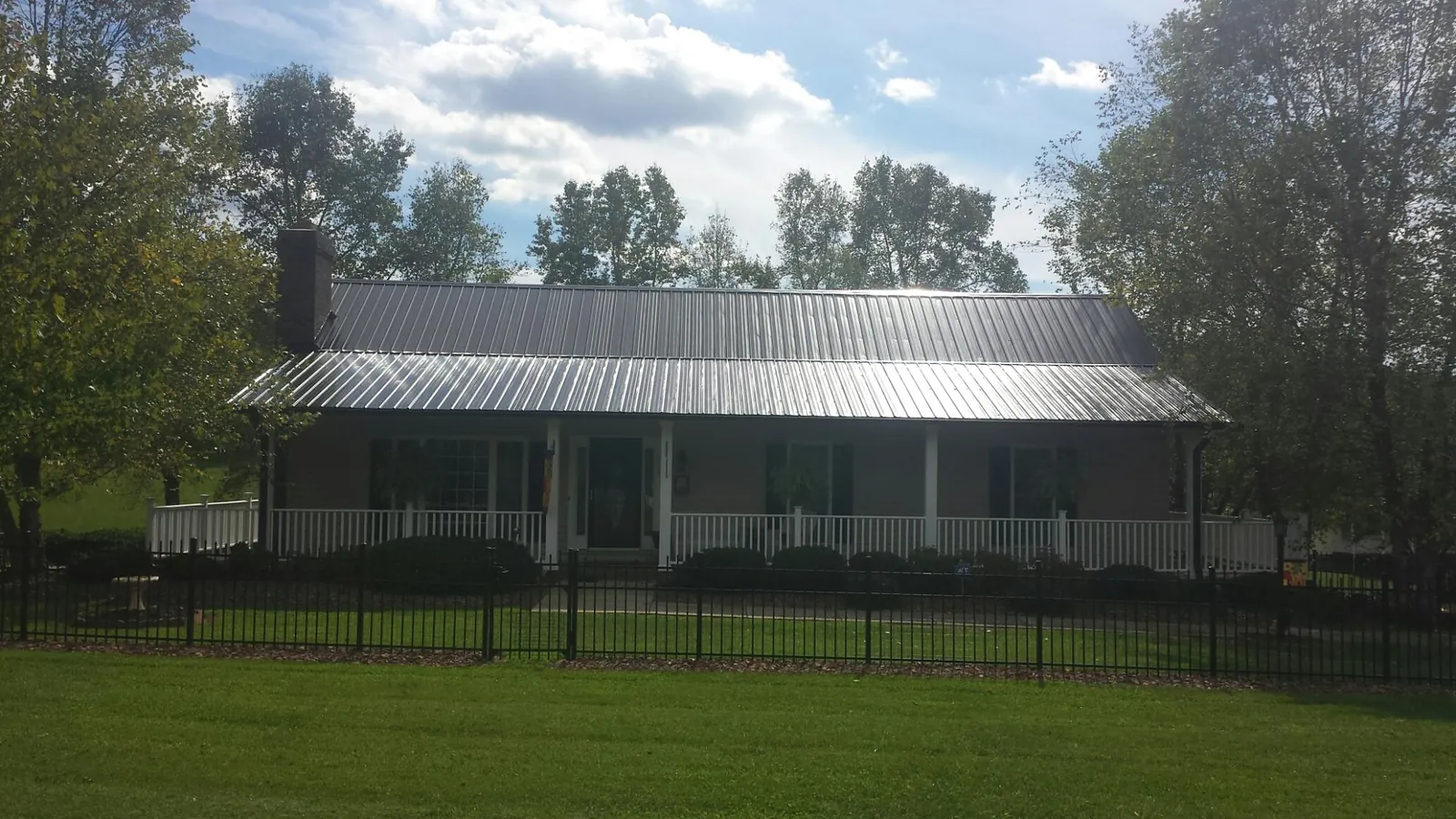 Gray metal roof on a brick ranch with a full width front porch — Gutter Guard Installation work by our crew in Fishing Creek