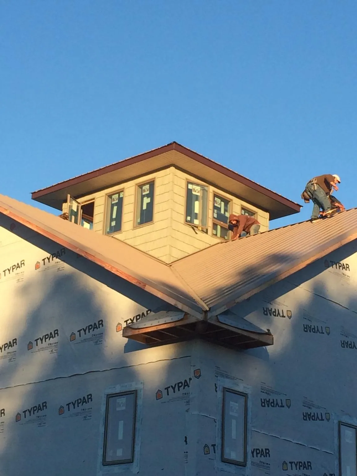Roofers working around a rooftop cupola on a new metal roof at sunset — Roof Waterproofing in Fishing Creek by Roofing Brothers